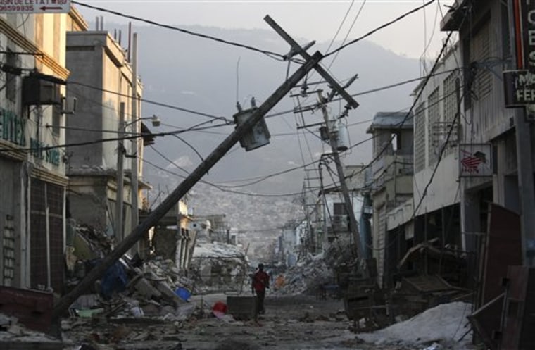 In this photo taken Feb. 16, a man walks down an earthquake damaged street with fallen electrical lines in downtown Port-au-Prince. More than a month after the temblor, electricity has been restored to almost half of Port-au-Prince.
